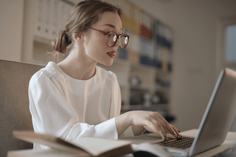 A girl with glasses typing on a laptop