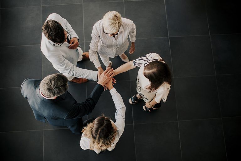 A group of business people holding hands together.